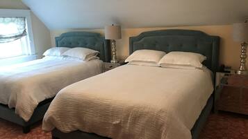 Ein Hotelzimmer mit zwei Betten, jeweils mit Kopfteil, Nachttischen inklusive Lampen und einem Kronleuchter.