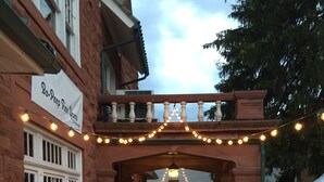 Une terrasse extérieure avec des tables et des chaises, un bâtiment en briques et des guirlandes lumineuses.