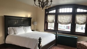 Un lit bien fait, avec une tête de lit sombre, une lampe de chevet et une fenêtre avec des rideaux.