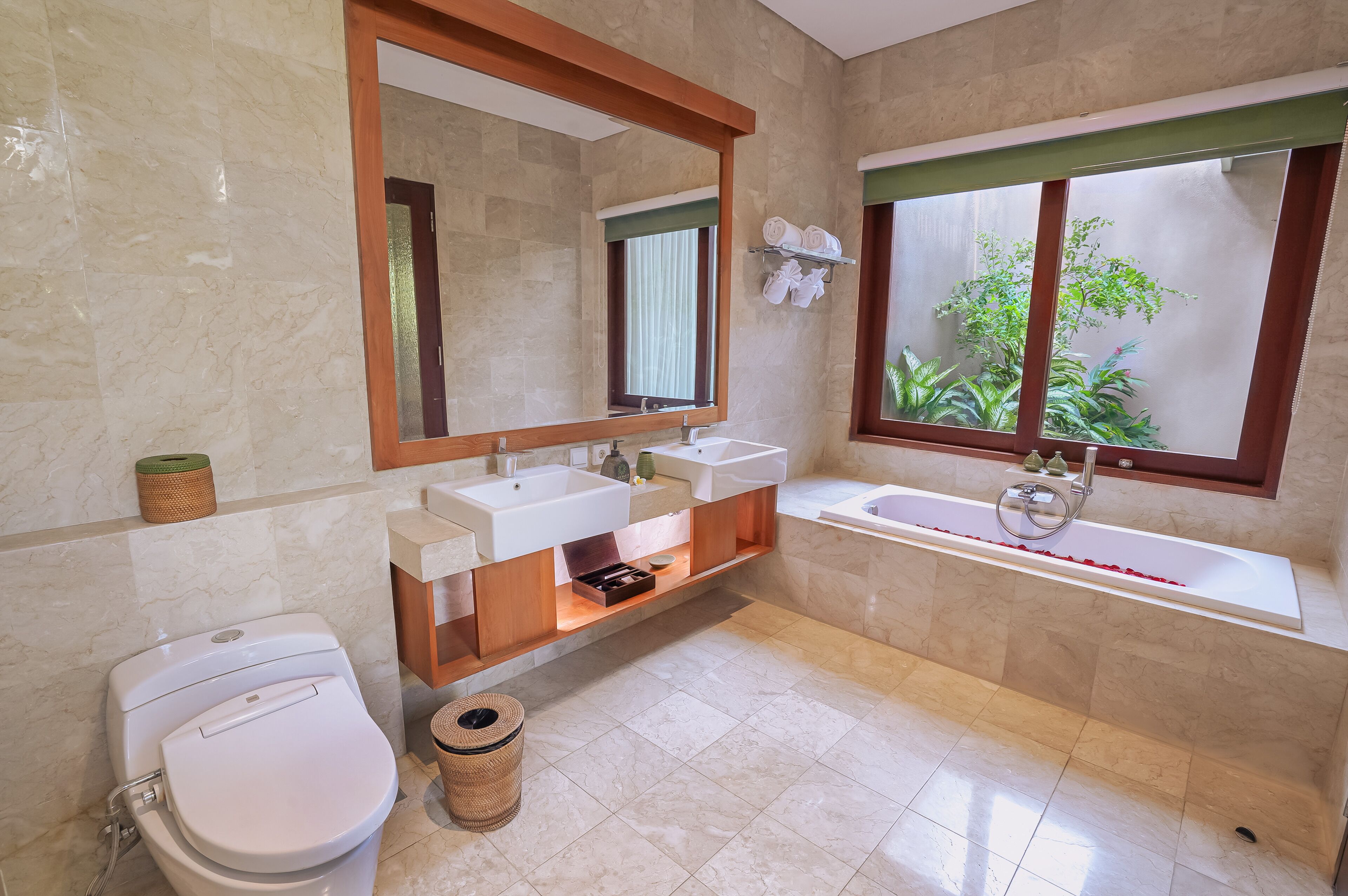 A modern bathroom with a toilet, two sinks, a bathtub, and a large mirror.