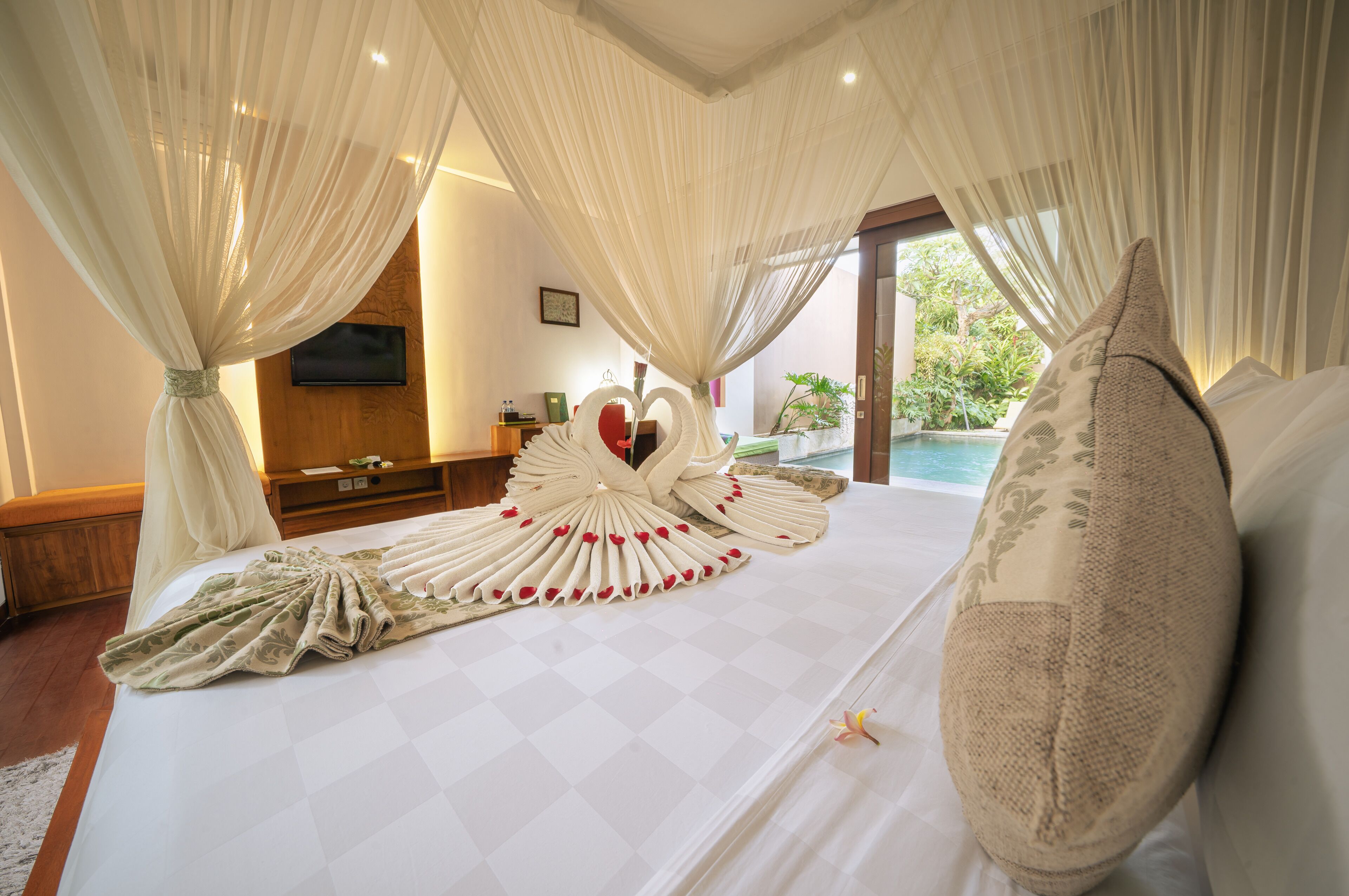 A hotel room with a large bed, a TV mounted on the wall, and a view of the outdoors.