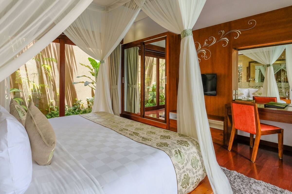 A bedroom with a canopy bed, a desk, and a chair.