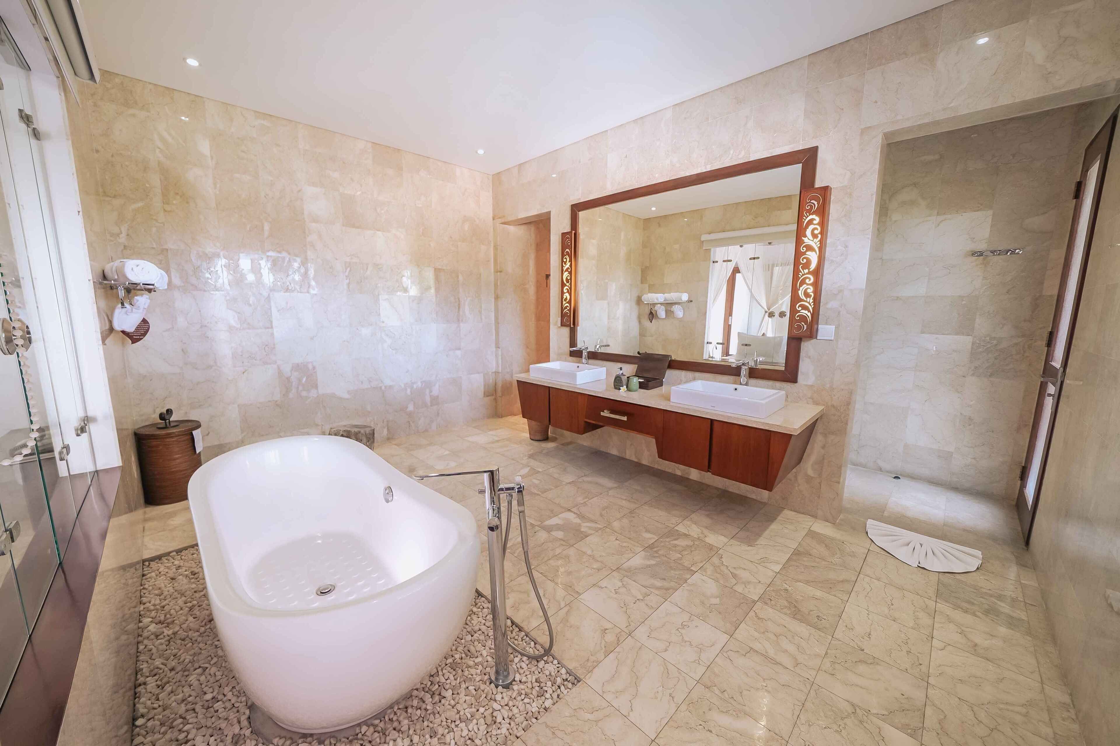 Un baño moderno con una bañera independiente, lavamanos dobles, un espejo grande y una zona de ducha.