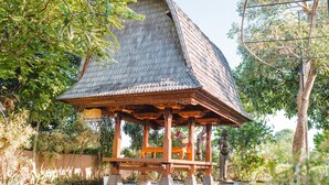 Ein traditioneller Pavillon mit Ziegeldach, umgeben von üppigem Grün und einem kleinen Wasserspiel.