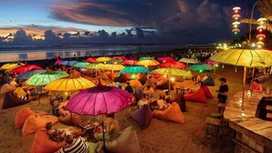 Eine Strandlage mit bunten Sonnenschirmen und Liegesäcken, die eine entspannte Sitzgelegenheit im Freien andeutet.