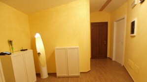 A hallway with wooden flooring, a white cabinet, a standing lamp, and a door. - Via Mameli 5 Inn (Sanremo)