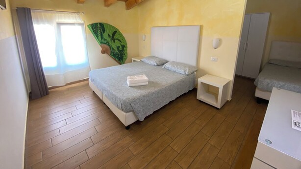 A bedroom with a bed, bedside tables, a fan, and a wardrobe. - Via Mameli 5 Inn (Sanremo)