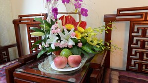 A table with a floral arrangement, two apples, and a decorative plate. - Little Hanoi Hotel (Hanoi)