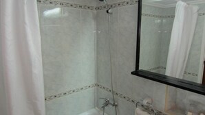 Ein Badezimmer mit Badewanne, Dusche, Waschbecken und Spiegel.