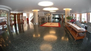 A spacious lobby with a polished marble floor, a central red carpet, and a long wooden reception desk. - Arenal (Sant Antoni de Portmany)