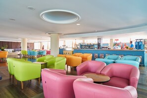 A brightly lit indoor space with colorful seating, a bar area, and a view of the outside. - Arenal (Sant Antoni de Portmany)