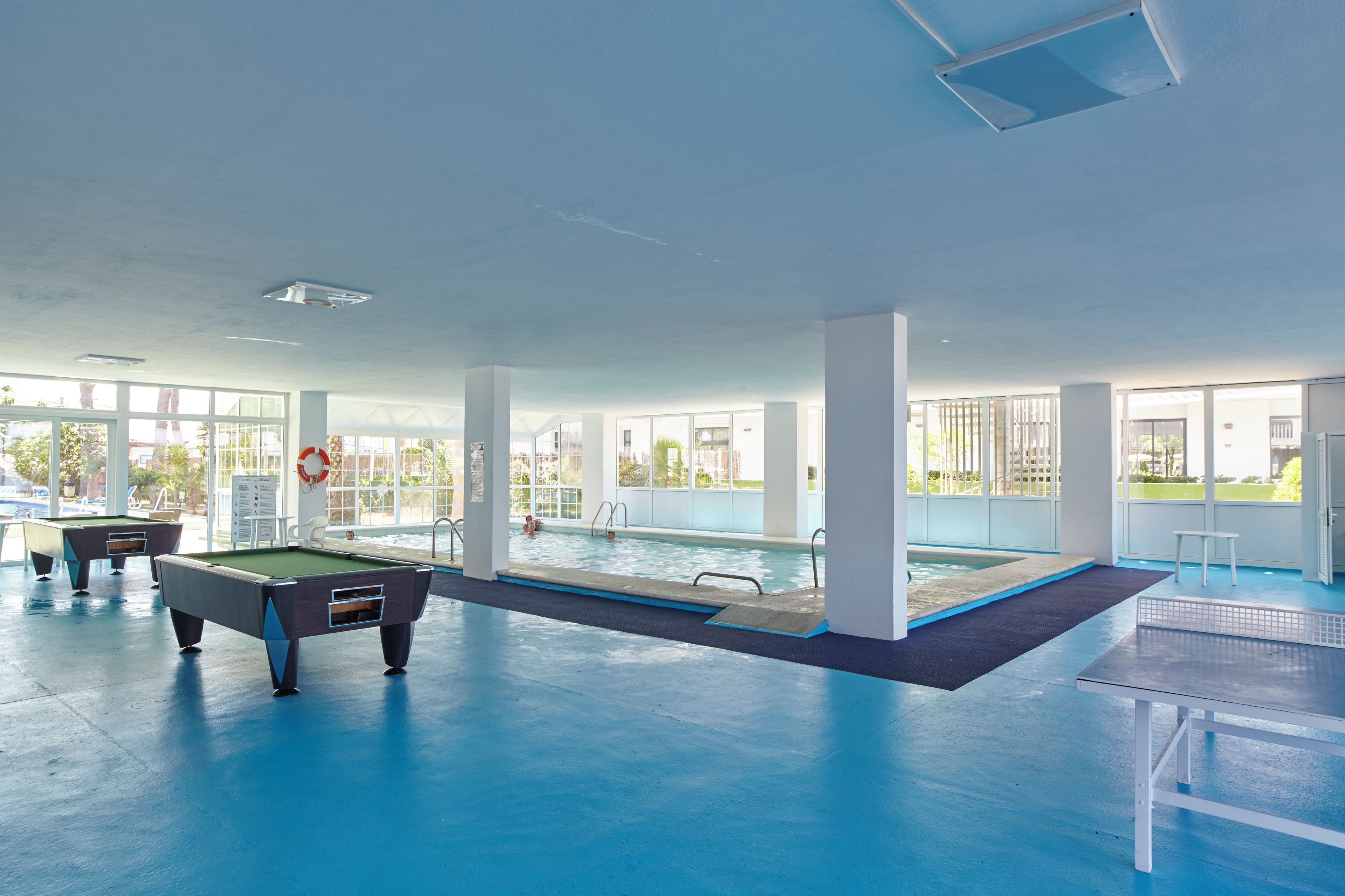 An indoor swimming pool area with a pool table and a lifebuoy.