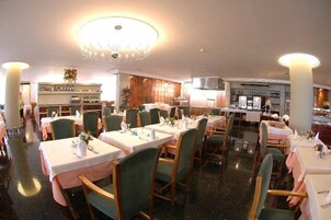 Un restaurante con varias mesas, sillas y una lámpara de cristal.