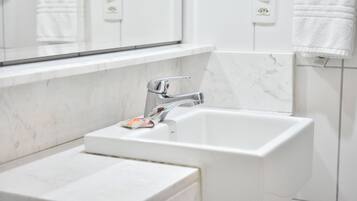 A modern bathroom with a white sink, chrome faucet, and marble tiles.