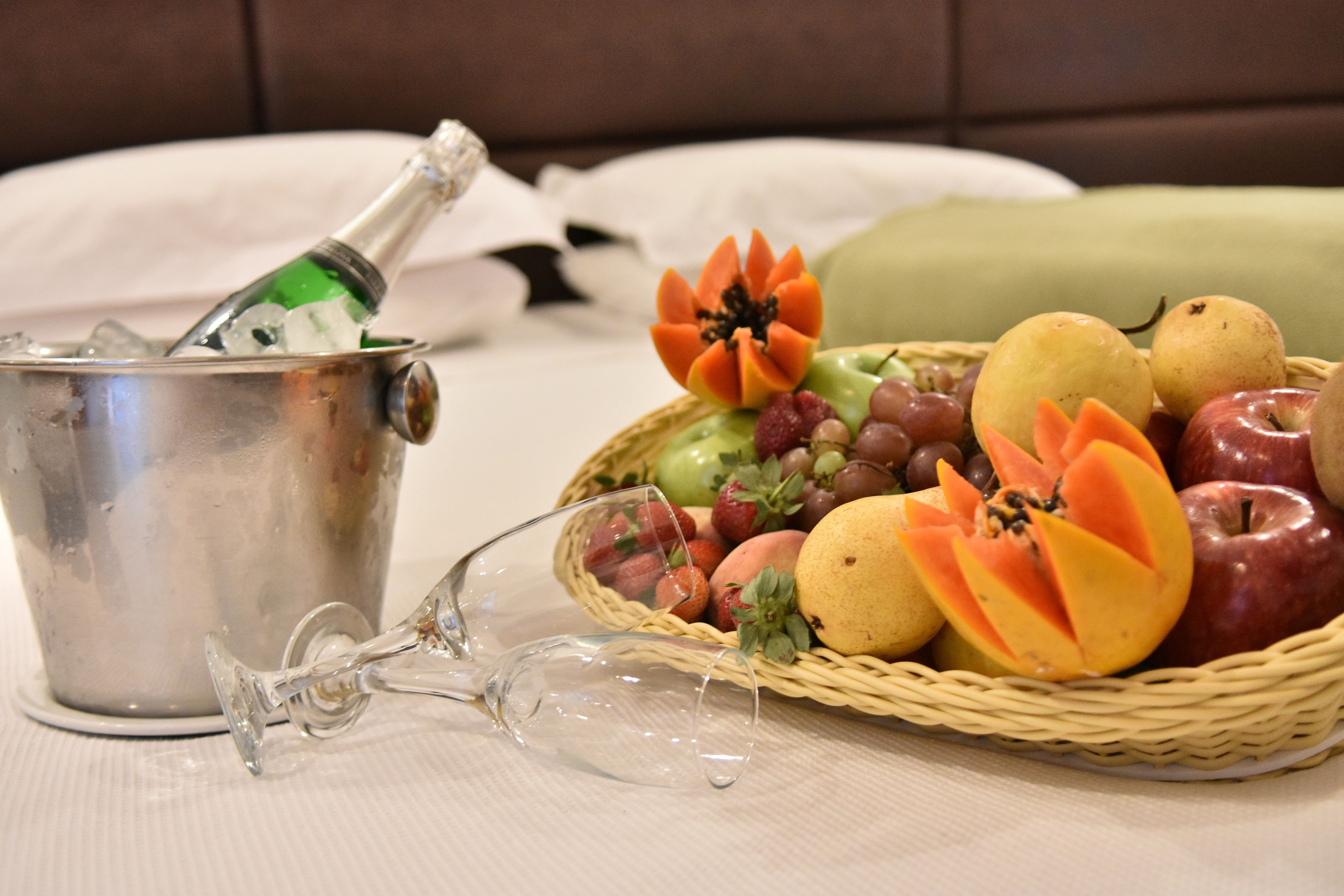 Un seau en métal, une bouteille, une paire de lunettes et un panier de fruits.