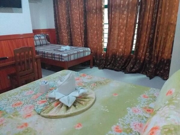 A room with a bed, a chair, a table, and curtains.