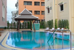 A swimming pool with a wooden deck, lounge chairs, and a gazebo. - Golden Villa (Pattaya)