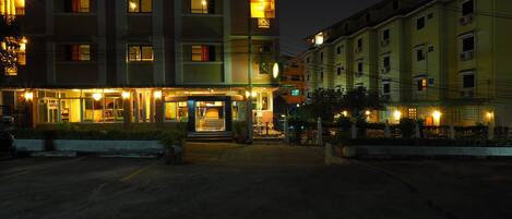 A multi-story hotel with illuminated windows and a well-lit entrance.
