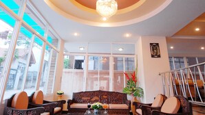 A lobby with a chandelier, wooden furniture, and large windows. - Golden Villa (Pattaya)