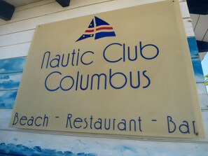 Une enseigne indiquant le «Nautic Club Columbus», précisant qu’il s’agit d’un établissement proposant une plage, un restaurant et un bar.