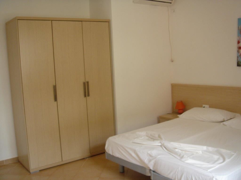 A bedroom with a bed, a wardrobe, and a nightstand.