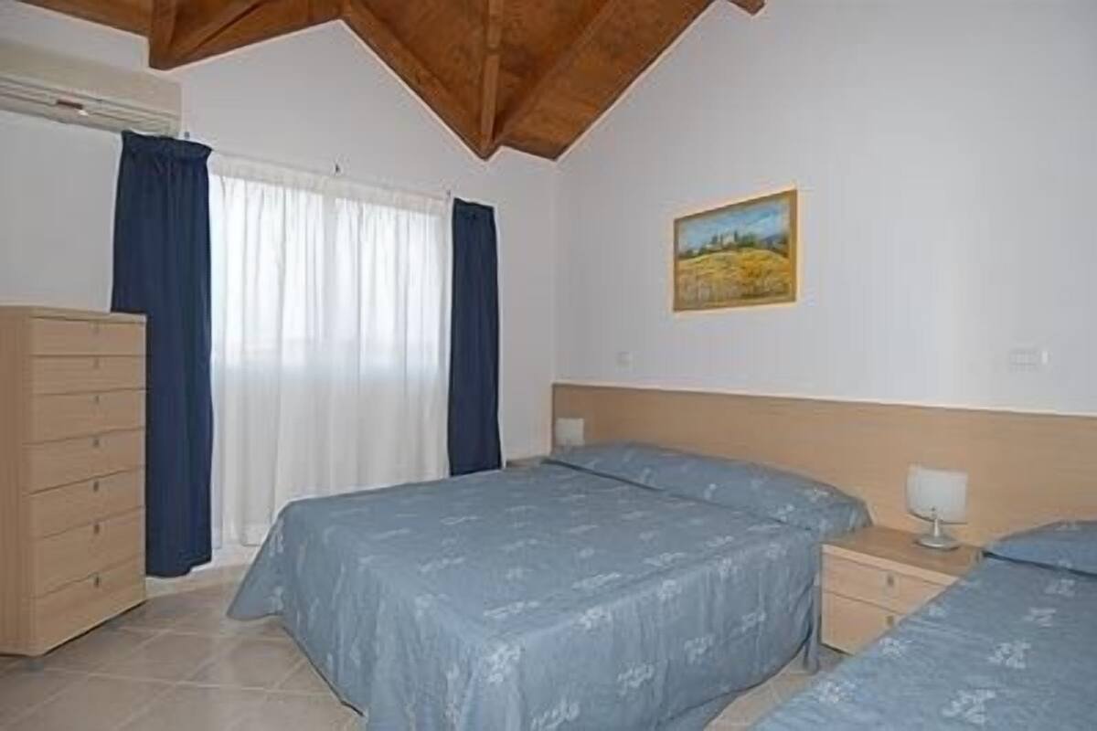A bedroom with a bed, a dresser, a nightstand, and a painting on the wall.