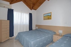 Un dormitorio con una cama, un aparador, una mesita de noche y un cuadro en la pared.