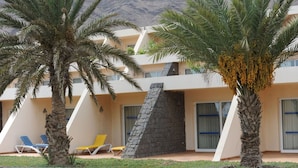 A hotel with a modern design, featuring a stone facade, multiple balconies, and palm trees. - Foya Branca by Flagworld Hotels (São Vicente)