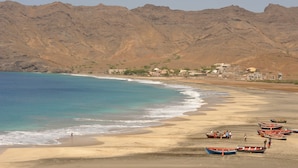 A beach with boats, a sandy shore, and mountains in the background. - Foya Branca by Flagworld Hotels (São Vicente)