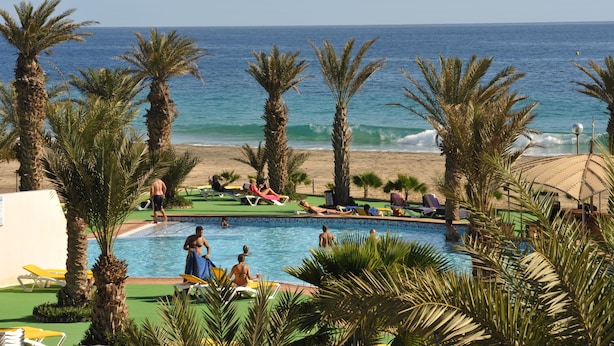 A pool area with palm trees, a beach, and the ocean in the background. - Foya Branca by Flagworld Hotels (São Vicente)