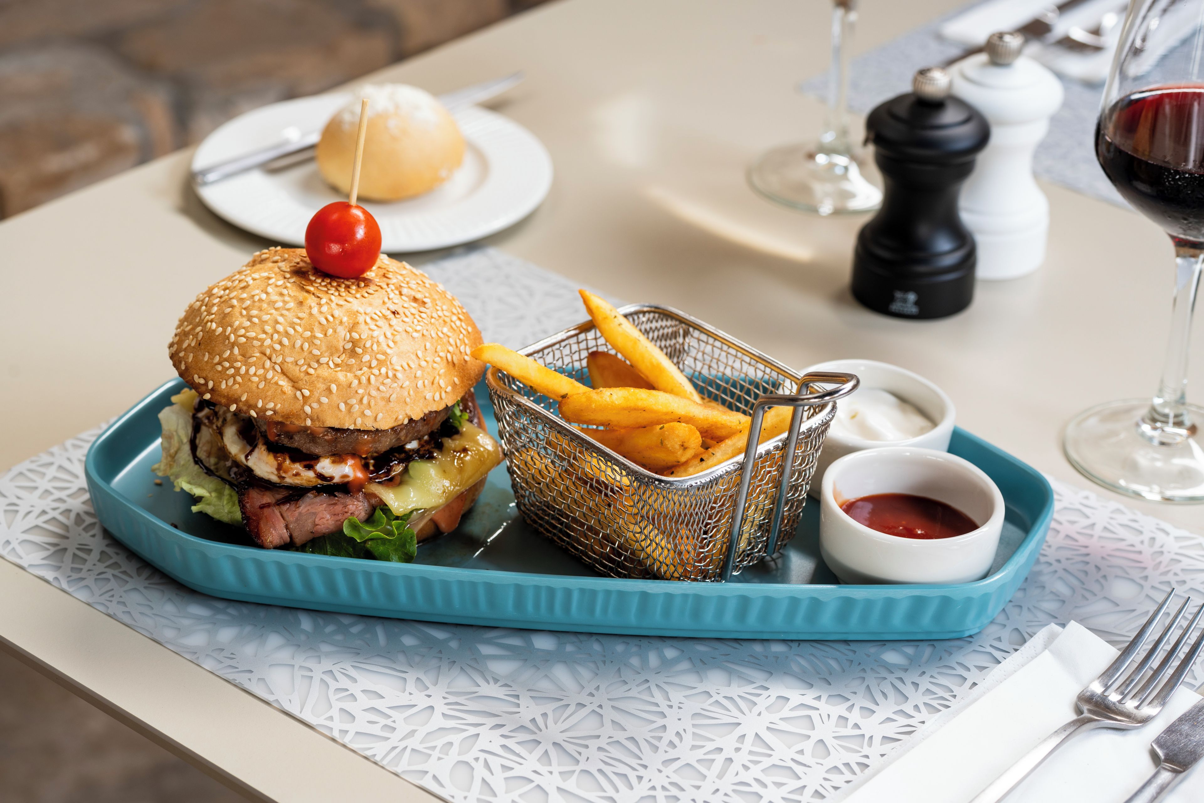 Una bandeja con una hamburguesa, papas fritas y kétchup.