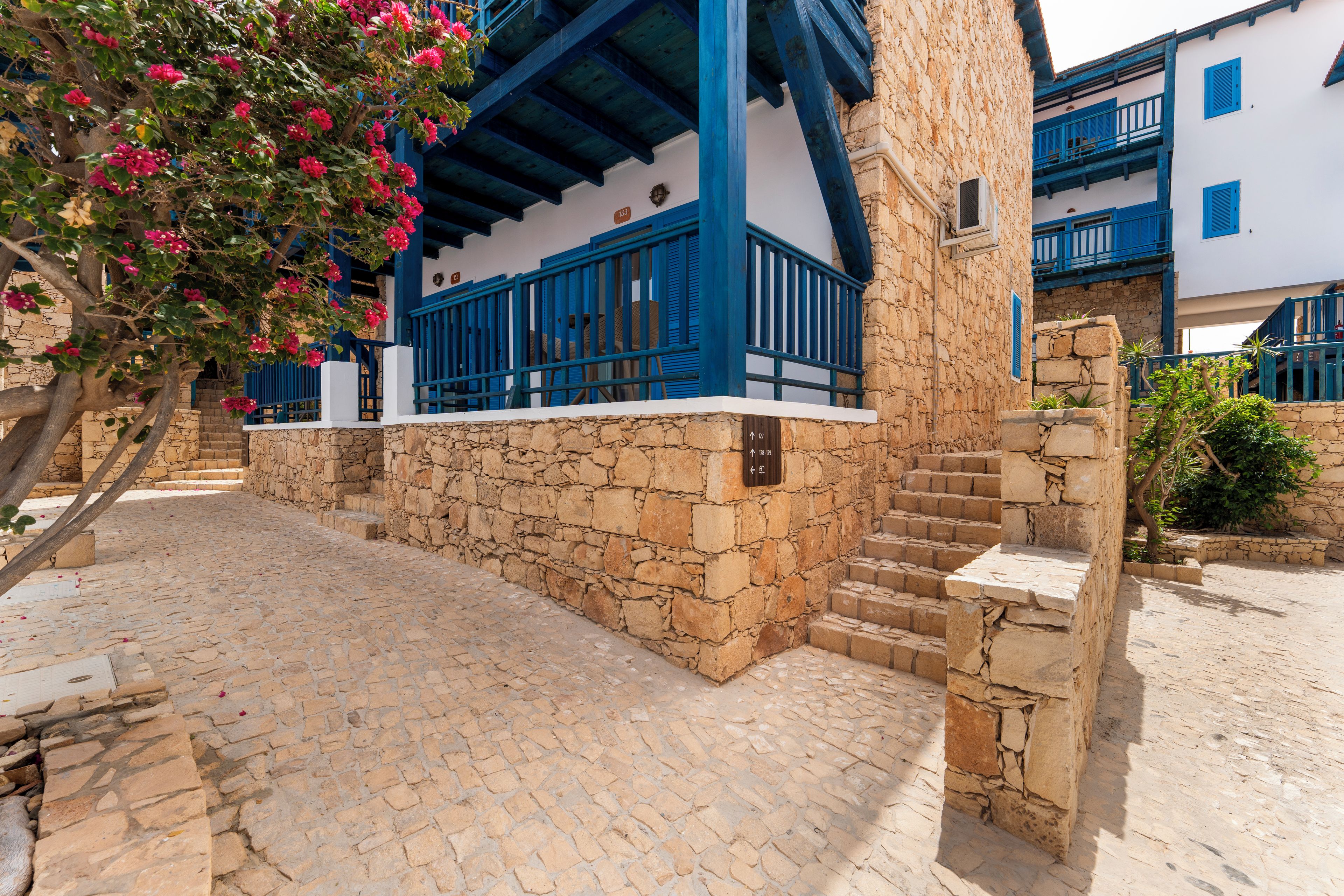 A stone building with blue accents and a staircase leading to a balcony.