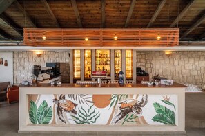 Eine Bar mit einer Steinwand, einer Holzbalkendecke und einem Wandgemälde von Meeresschildkröten.