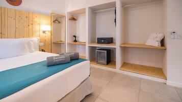 Habitación de hotel con cama, minibar, armario y un escritorio pequeño.