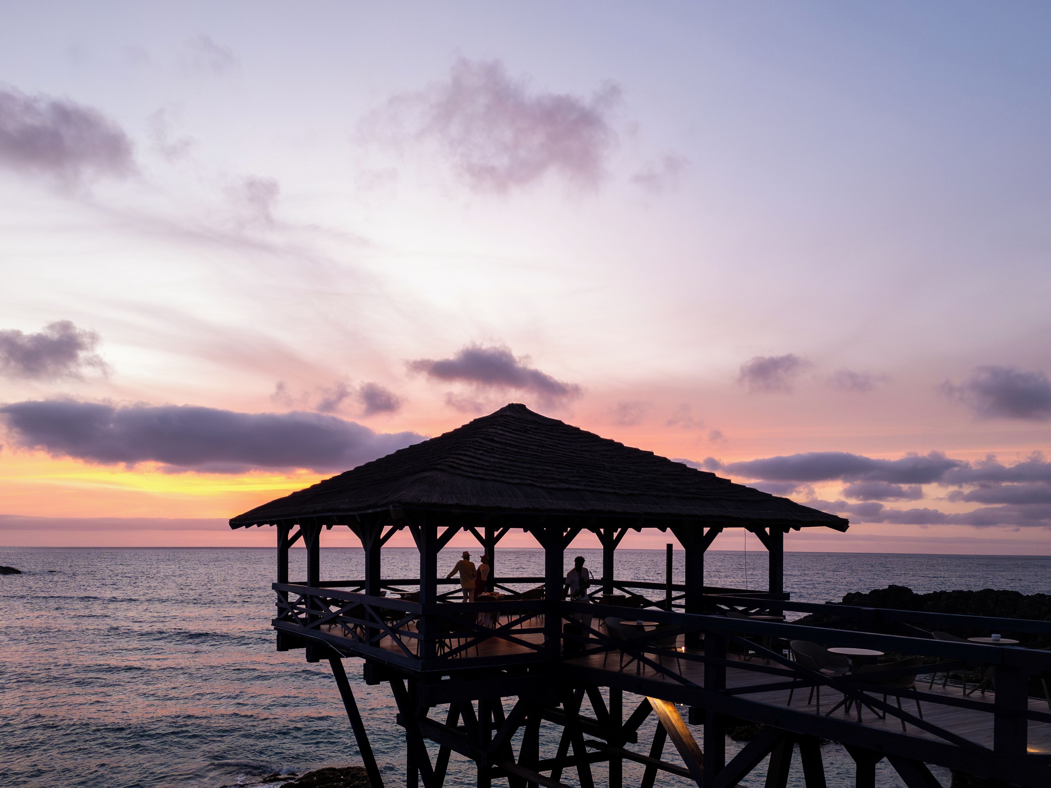 A pier structure with a roof, overlooking the sea.