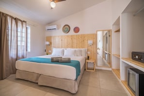 Quarto de hotel com cama, mesa de cabeceira, televisão e espelho.