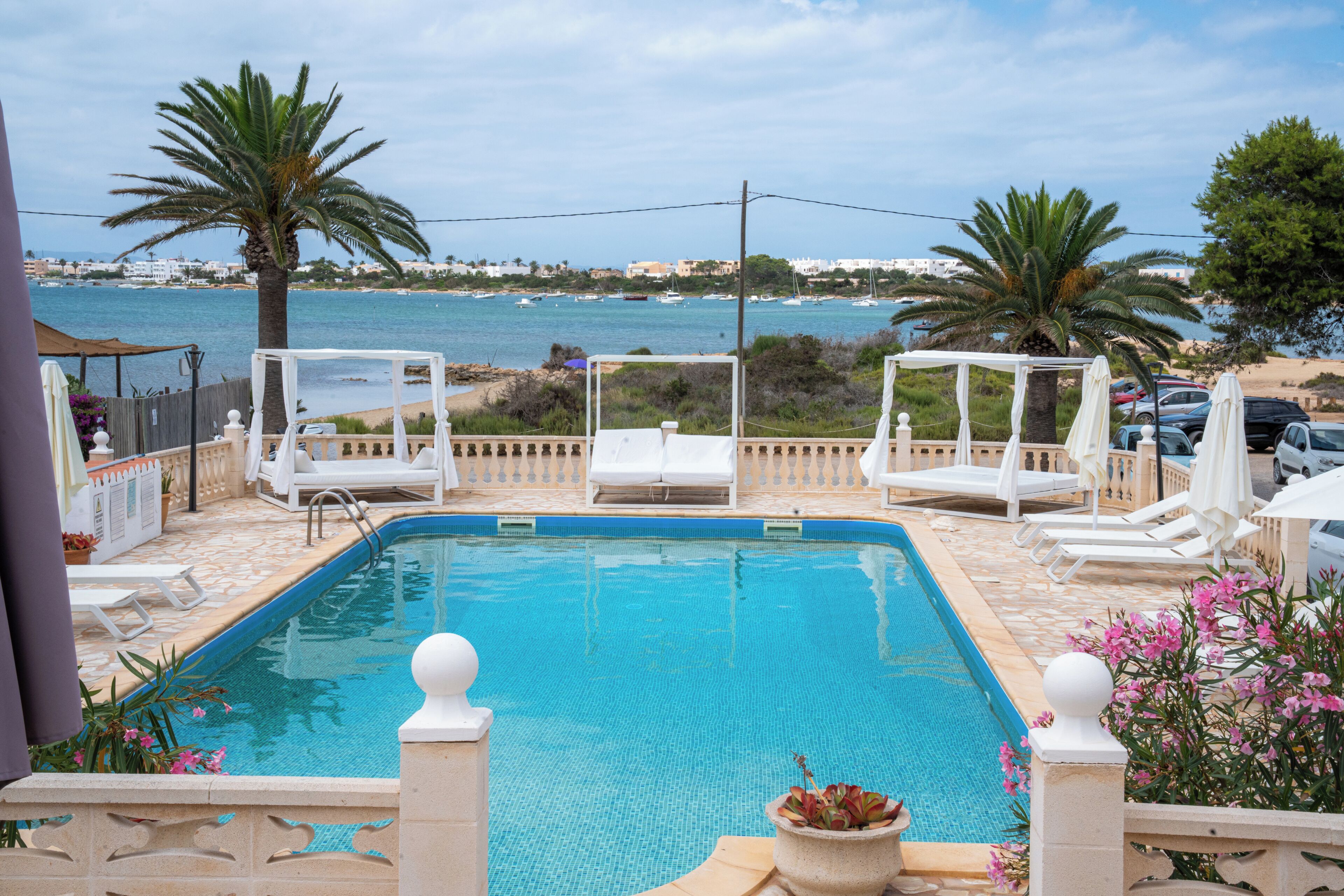 A swimming pool with lounge chairs and a view of the sea.