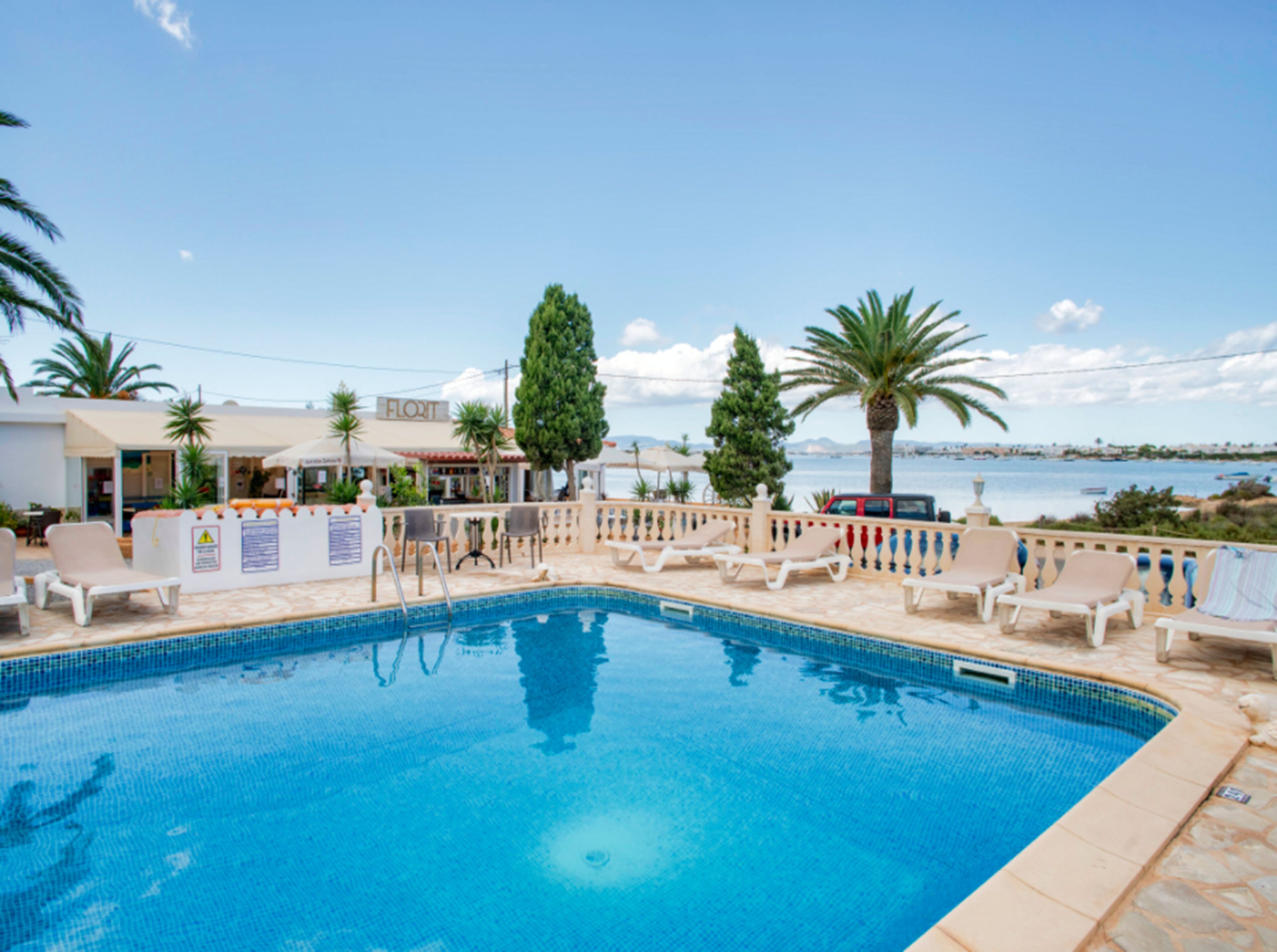 Una piscina al aire libre, sombrillas, sillones reclinables de piscina