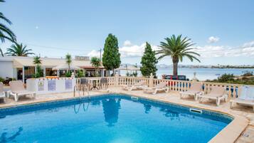Una piscina al aire libre, sombrillas, sillones reclinables de piscina