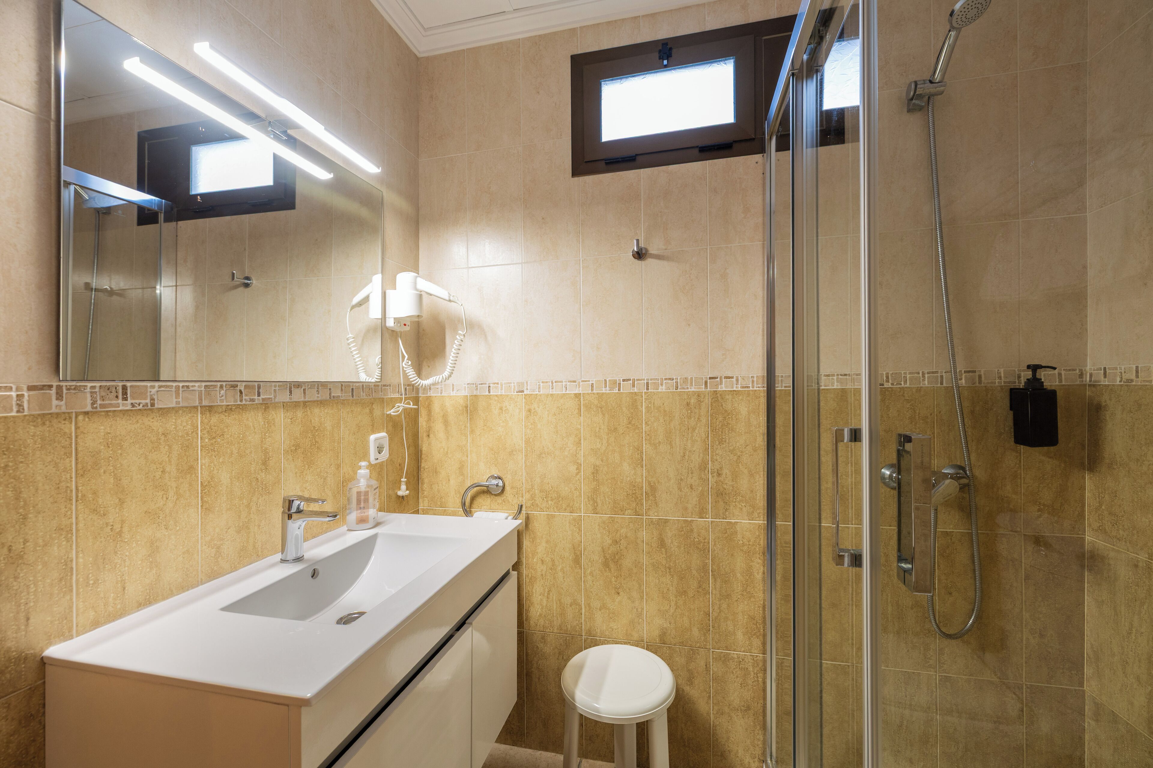 A bathroom with a sink, mirror, and shower.