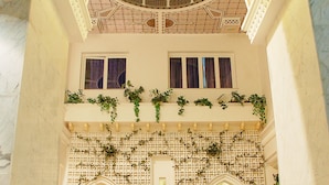 A grand lobby with a high ceiling, a piano, seating area, and a decorative wall with climbing plants. - Hotel Byzance (Nabeul)