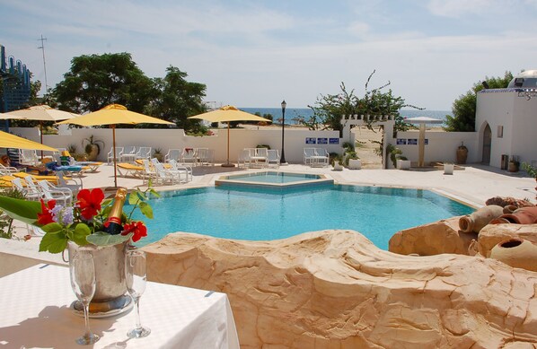 En sÀsongsöppen utomhuspool, parasoller och solstolar