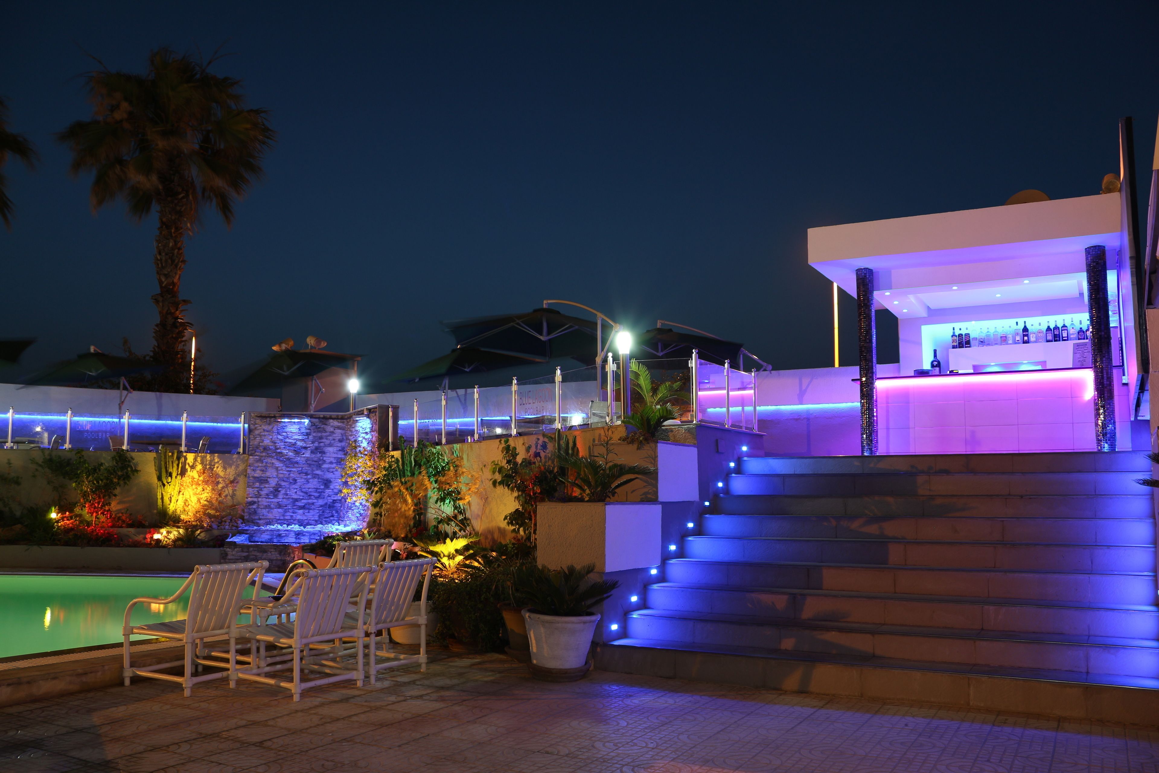 A poolside area with outdoor seating, a bar, and a staircase leading to an upper level.