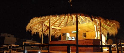 A wooden structure with a thatched roof, likely a beach hut or small building, with a wooden deck in front.