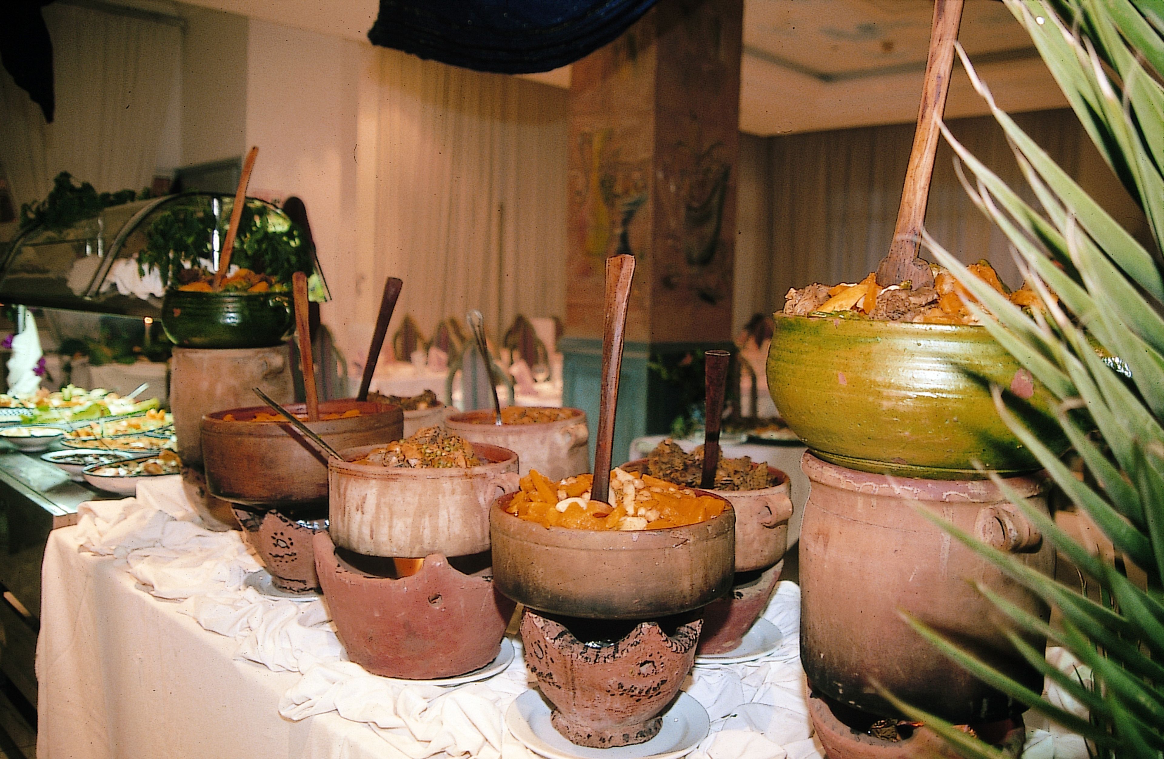 Una mesa de buffet con diversos platos servidos en ollas de barro tradicionales.