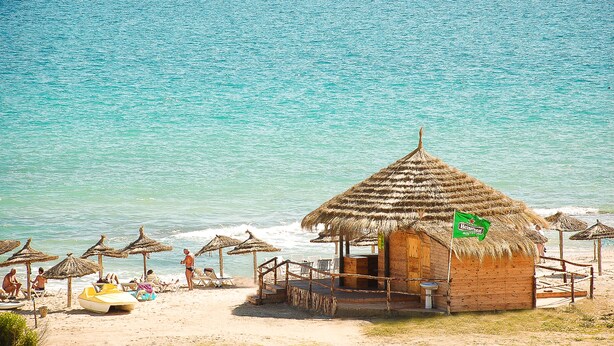 A beachside hut with a thatched roof, a small bar area, and a view of the ocean. - Hotel Byzance (Nabeul)