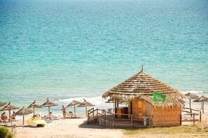 A beachside hut with a thatched roof, a small bar area, and a view of the ocean.
