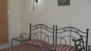A bedroom with a bed, a nightstand, a wall-mounted lamp, and a framed picture. - Hotel Les Citronniers (Hammamet)