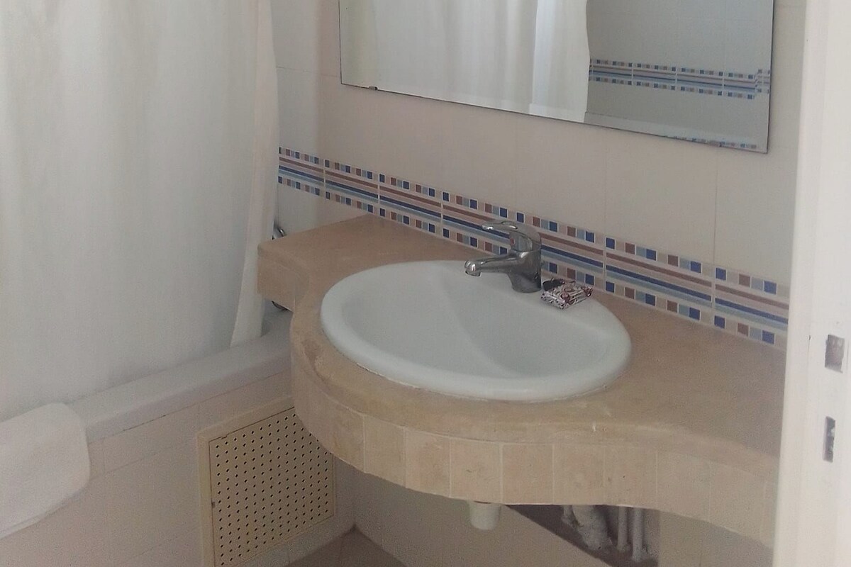 A bathroom with a shower curtain, a sink with a mirror, and a towel rack.