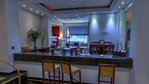 A modern kitchen with a marble countertop, three bar stools, a large window, and a view of the outside. - Shelton Hotel (Serra Negra)